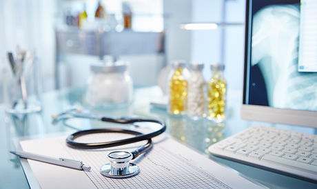 Medical office desk with stethoscope, clipboard, and x-ray