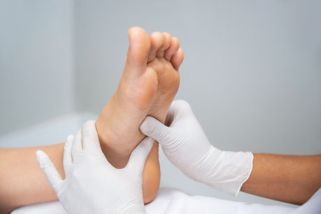 Gloved hands examining a patient's foot — Oak Ridges Foot Clinic